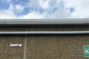 PP Gutters commercial roof and gutter cleaning services. Showing a damaged commercial gutter after being repaired.