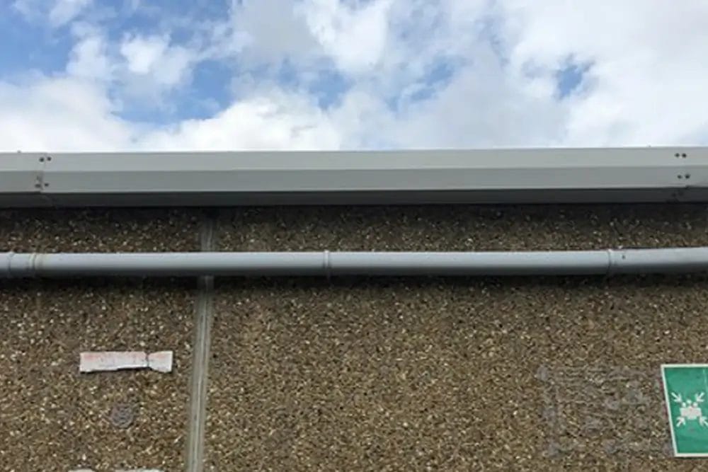 PP Gutters commercial roof and gutter cleaning services. Showing a damaged commercial gutter after being repaired.