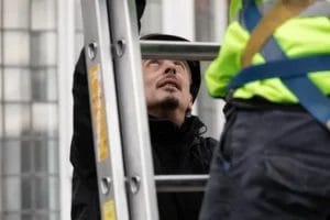 PP Gutters, the roof and gutter cleaning specialists. Image of a PP Gutters technician supporting the base of a ladder