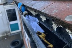 School gutter cleaning in London, Watford and High Wycombe - photo of a gutter at St Mary's CofE School in Aylesbury, before it's been cleared of various debris by PP Gutters.