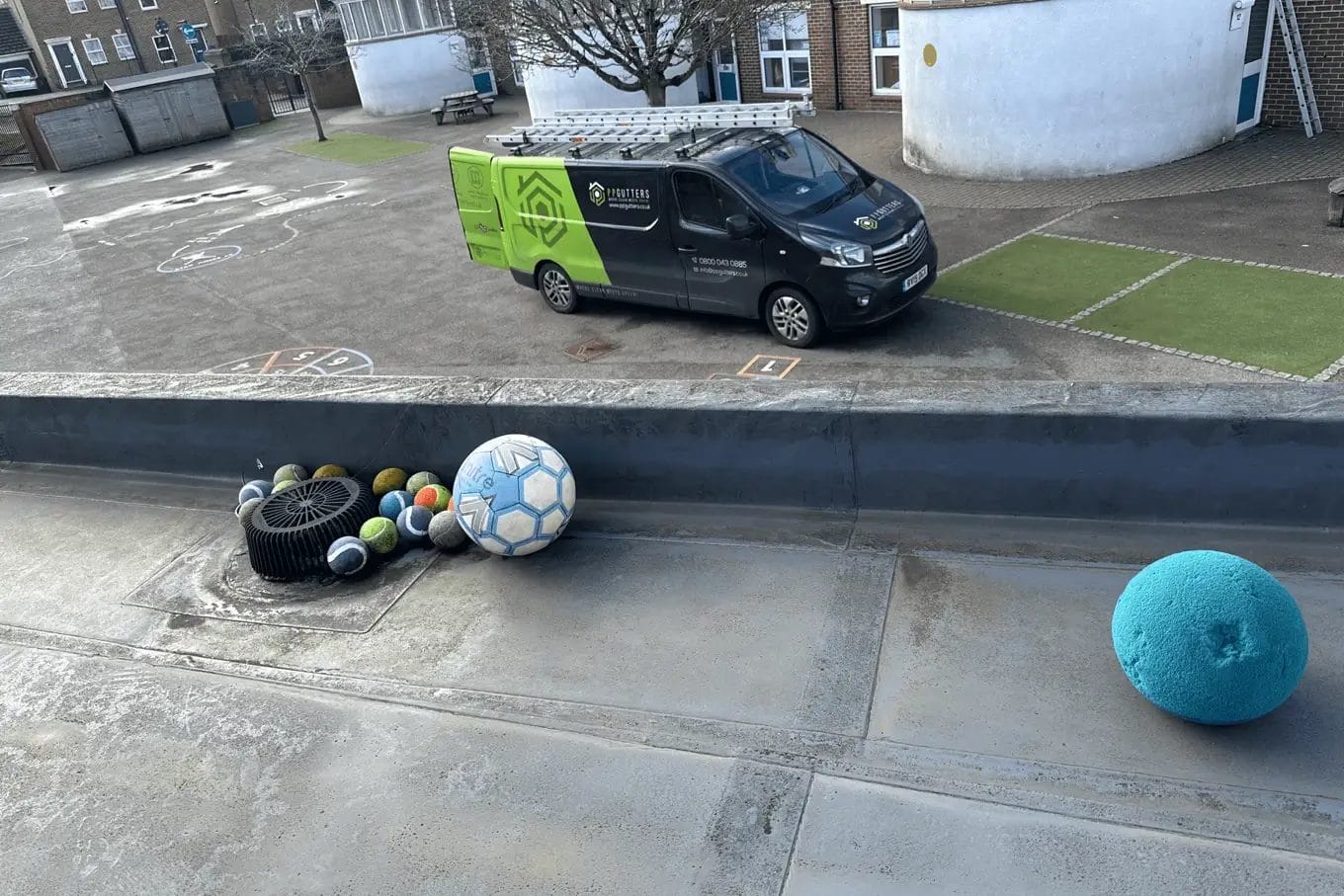 School gutter and roof clearing in London, Watford and High Wycombe - photo of a flat roof with built in gutter at St Mary's CofE School in Aylesbury, before it's been cleared of various balls and debris by PP Gutters.