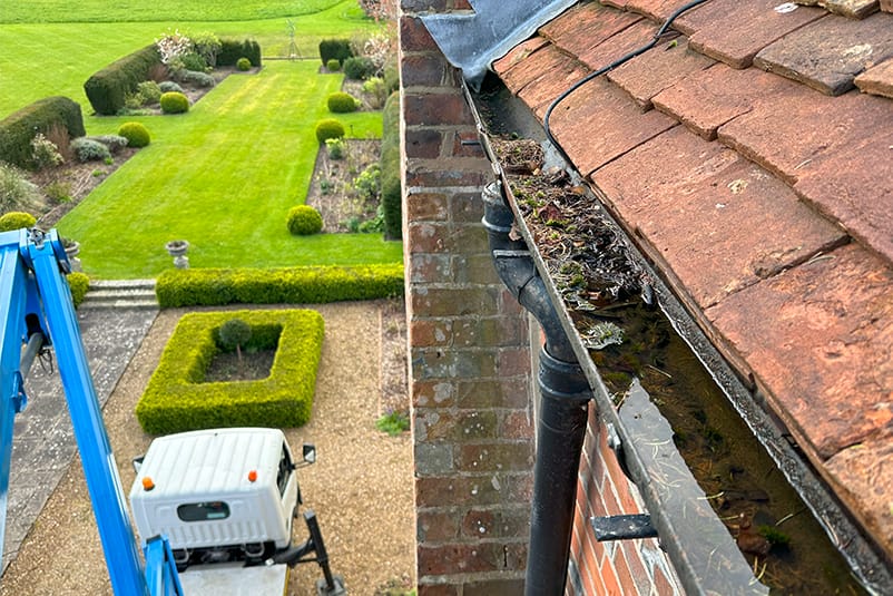Blocked gutter overflowing with water on an older UK home, showing one of the most common gutter problems in older UK homes